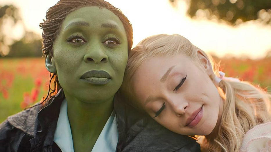 A young woman with green-hued skin looks away as another young woman rests her head on her shoulder