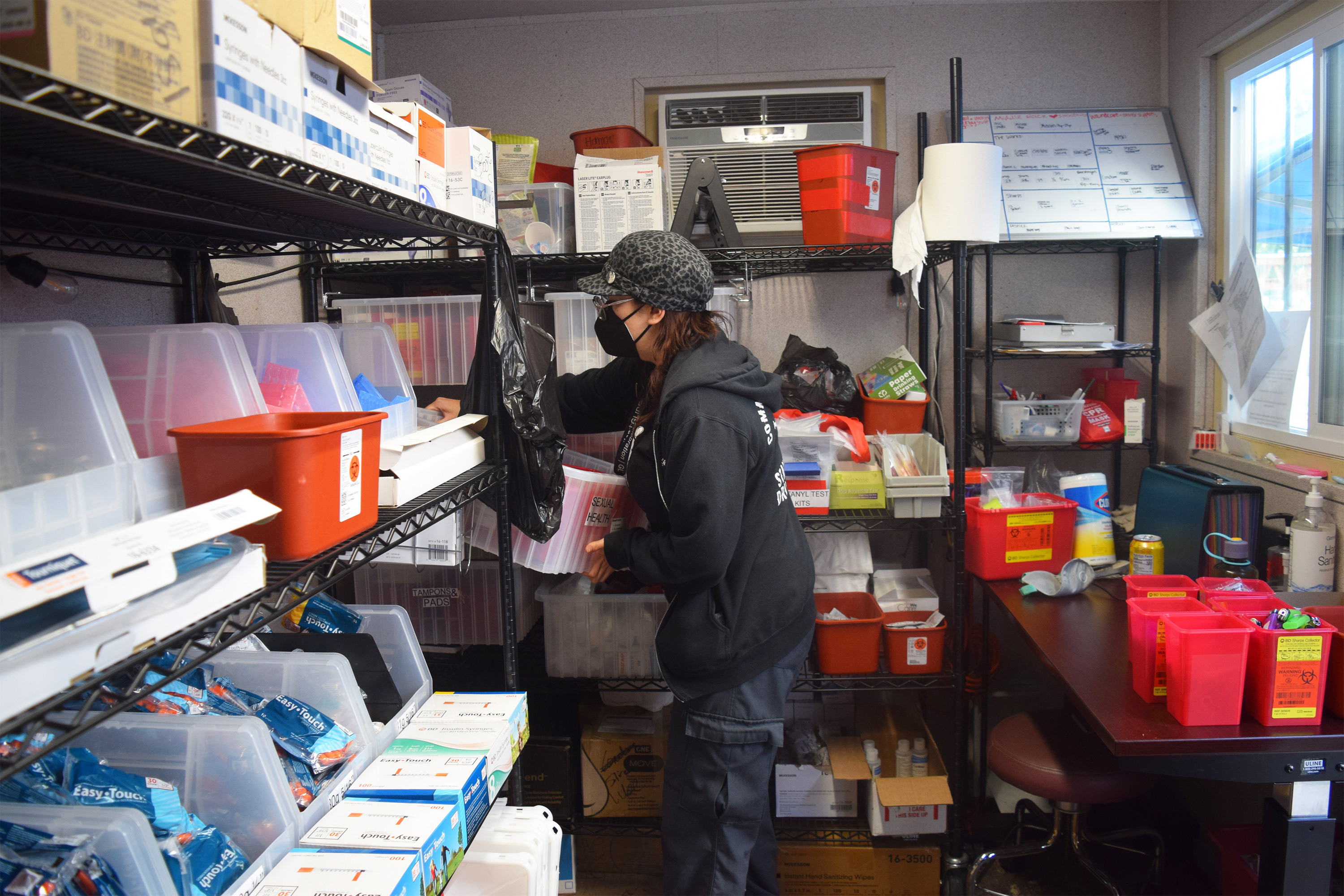 A photo of Sky Contreras reaching into a bin, surrounded by others with medical supplies.