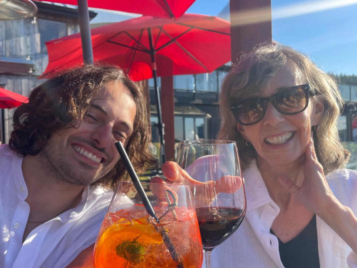 Gemma Lewis's boyfriend and mom both drinking cocktails outside under a red umbrella.