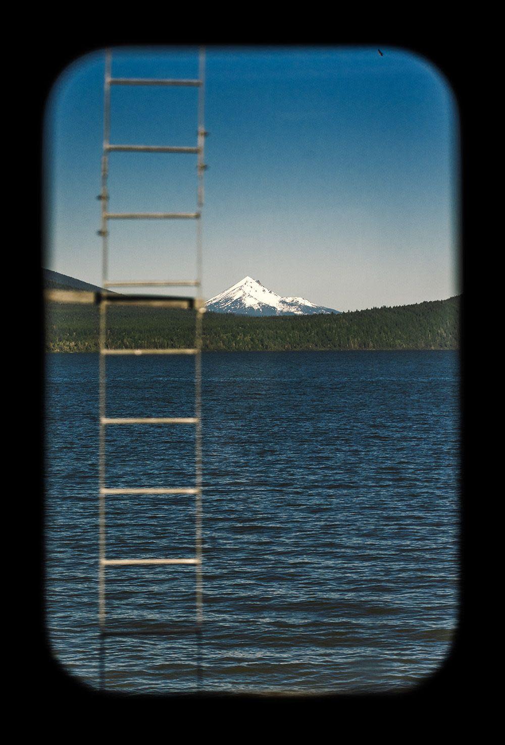 A ladder coming out of a lake in front of snow capped mountains