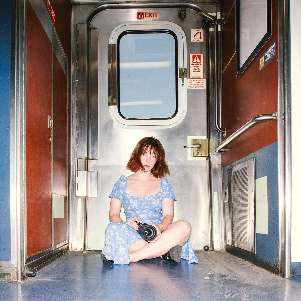 Katie Edwards sitting in the vestibule of a train with her camera