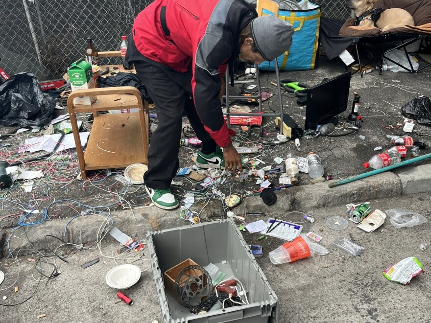 Randy Hauser hurries to gather up his possessions under an overpass south of Market Street, as city workers approach for a sweep.