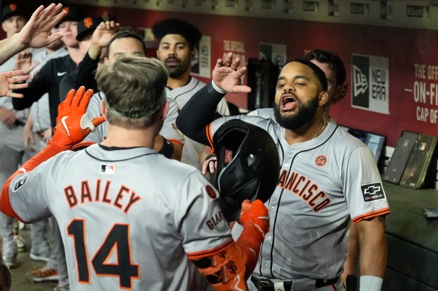 San Francisco Giants' Patrick Bailey (14) celebrates in the dugout with Heliot Ramos, right, and others after hitting a home run during the second inning of a baseball game against the Arizona Diamondbacks, Tuesday, Sept. 24, 2024, in Phoenix. (AP Photo/Ross D. Franklin)