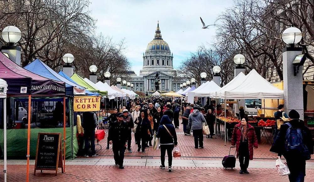 People walk around a farmers market outside of SF City Hall