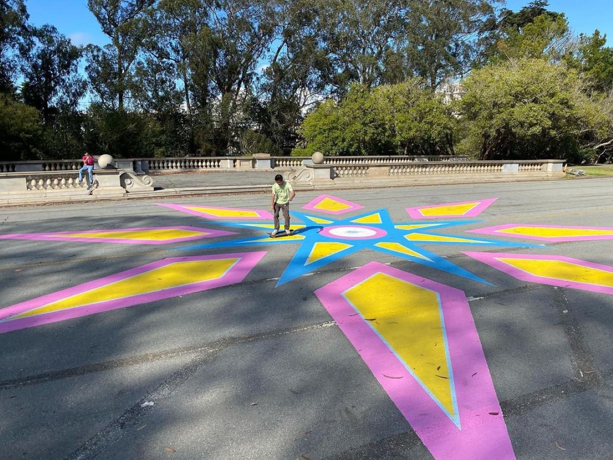 A pink, yellow, and blue star-shaped ground mural on JFK Drive.